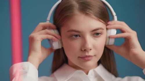Young Woman Puts on Headphones and Listens to Music. Portrait of Smiling