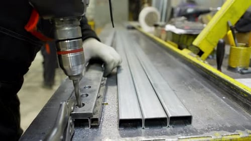 Erfahrener Ingenieur, der eine Bohrmaschine an Metallkonstruktionen in einer Fabrikumgebung bedient