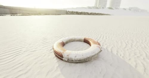 Salvavidas descansando en una playa de arena cerca de edificios costeros al atardecer