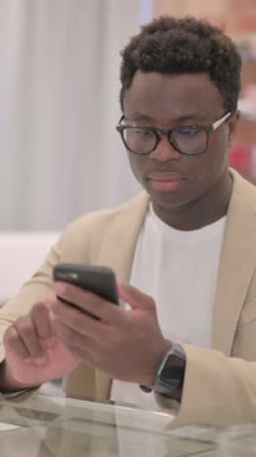 Enthusiastic Man Reacts to Phone at Glass Counter