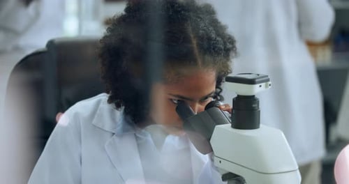 Young Woman Analyzing Sample Under Microscope in Lab