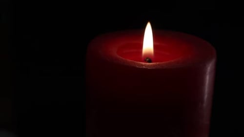Burning red candle on turntable isolated on black background