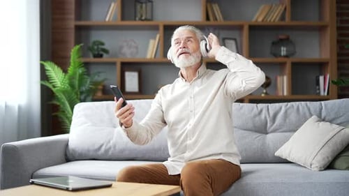 Senior Man Listening with Wireless Headphones Indoors