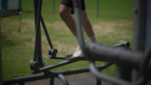 Young Adult on Elliptical Machine in Urban Park