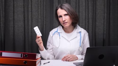 Female Doctor Showing Medicine Blister Pack at Office Desk