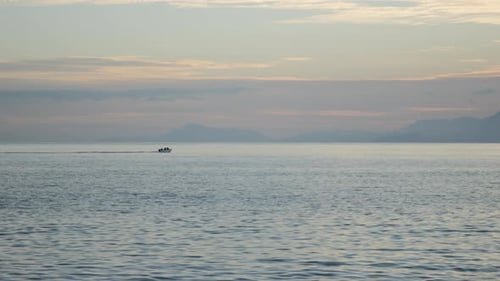 Fishing Boat in the Open Sea Sails Toward the Mountains and Into the Sunset