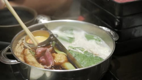 poner una rodaja de oporto en un shabu shabu japonés con verduras, carne y tobogán de cerdo.