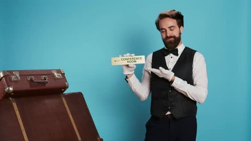 Man Points to Conference Room Sign with Luggage