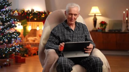 Handsome Senior Greyhaired Man in Rocking Chair Waving Talking at Digital Tablet Web Chat Smiling