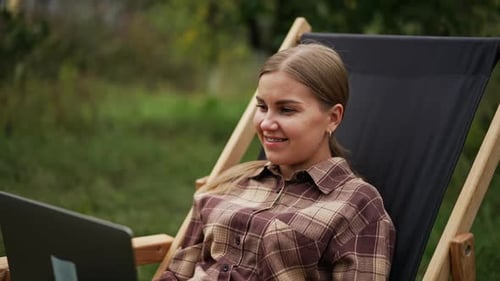 Lifestyle elegant business lady. Young charming woman working with laptop in garden.