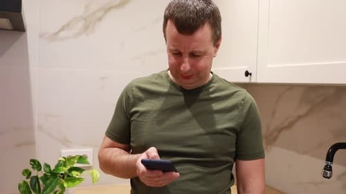 Man Looking at Smartphone in Modern Kitchen