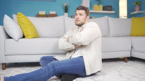 The depressed young man sitting alone on the floor thinks about the events that have happened.