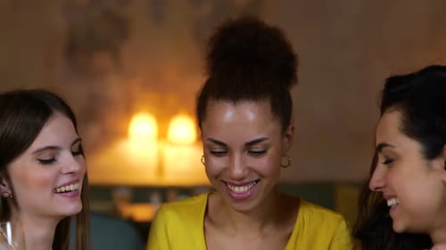 Happy Female Friends Looking at Mobile Phone Screen While Sitting in the Restaurant Drinking