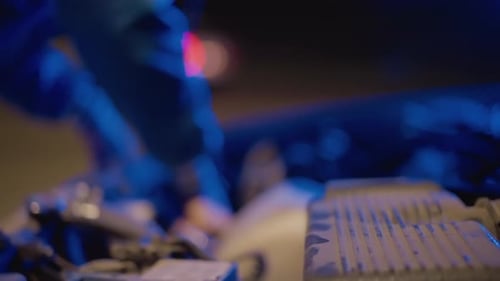 Man Repairing a Car Engine at Night
