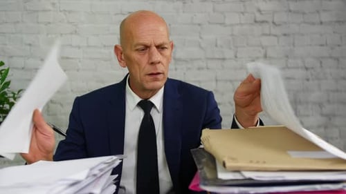 Stressed Businessman Overwhelmed by Paperwork in Office