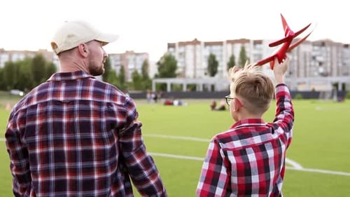 Father and child play with airplane at sunset in park. Happy family dream of becoming a pilot.