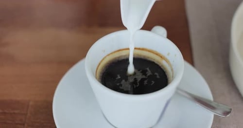 Pouring Milk Into Coffee Cup Coffee with Froth Close Up Hot Coffee in the Morning