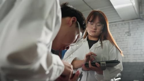 Engineer Measuring Engine Dimensions While Colleague Records Data on Tablet