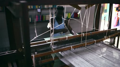 Man, floor treadle loom and clothing production at textile factory, manufacturing and craftsmanship
