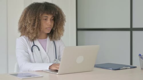 African Female Doctor Working on Laptop in Clinic