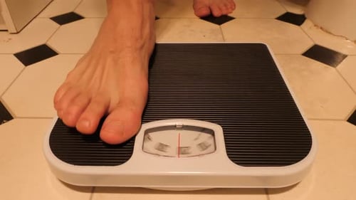 Front on view of person stepping on and off scales with weight in kilograms