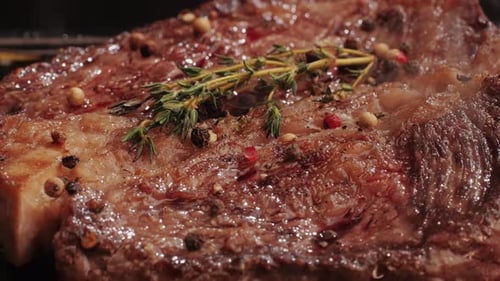 Fresh Marbled Beef with Pepper Salt and Rosemary Closeup Macro Cooking Juicy Steak on Grill with Oil
