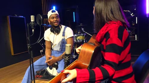 Musicians recording music in studio with acoustic guitar