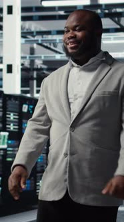 Vertical Video Smiling Engineer Walking in Data Center Facility with Rows of Supercomputers