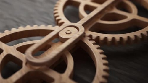 Looping animation of two wooden gears connected by a mechanical shaft.