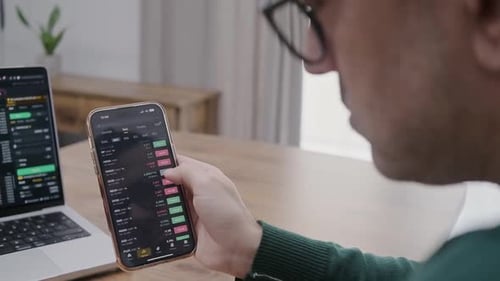 Man Analysing Stock Market Charts on Laptop and Smartphone Bitcoin and Crypto Currency Investment