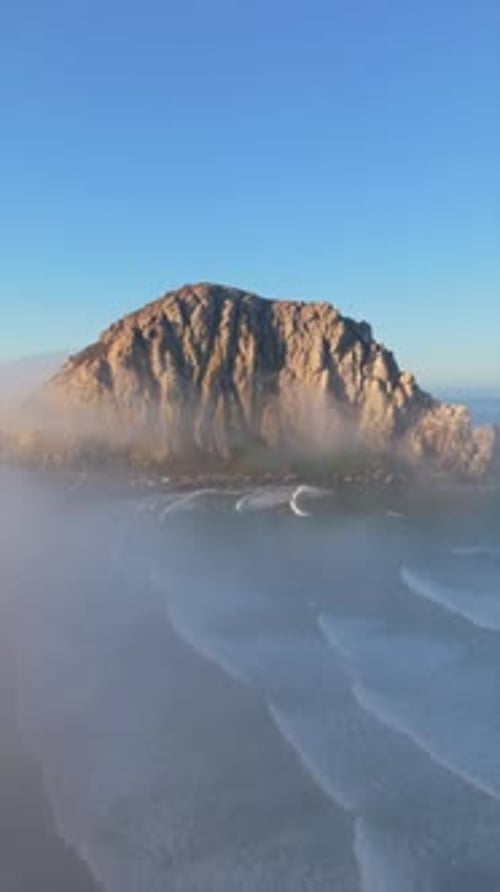 A Majestic Coastal Rock Formation Beautifully Surrounded By Mist and Rolling Waves