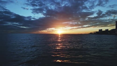 Aerial view of sun under the clouds over the sea, moving backwards