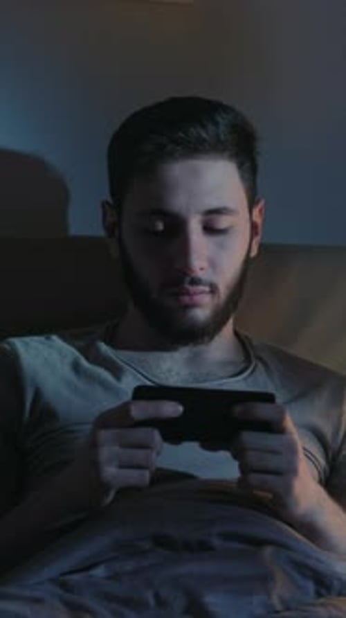 Young Adult in Bed Using Phone at Night
