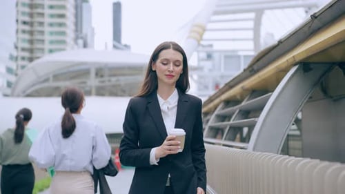 Caucasian businesswoman hold a coffee while walk outdoors in the city.