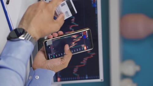 Vertical video of The man who monitors the stock market makes purchases with a credit card.
