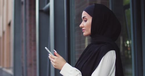 Close Up Portrait of Arabic Woman in Traditional Headscarves Looking at Phone and Smiling Pretty