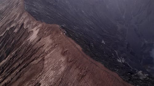 Aerial view of smoking volcano with man walking on summit, Indonesia.