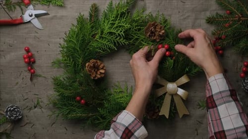 Person Arranging a Christmas Wreath with Berries