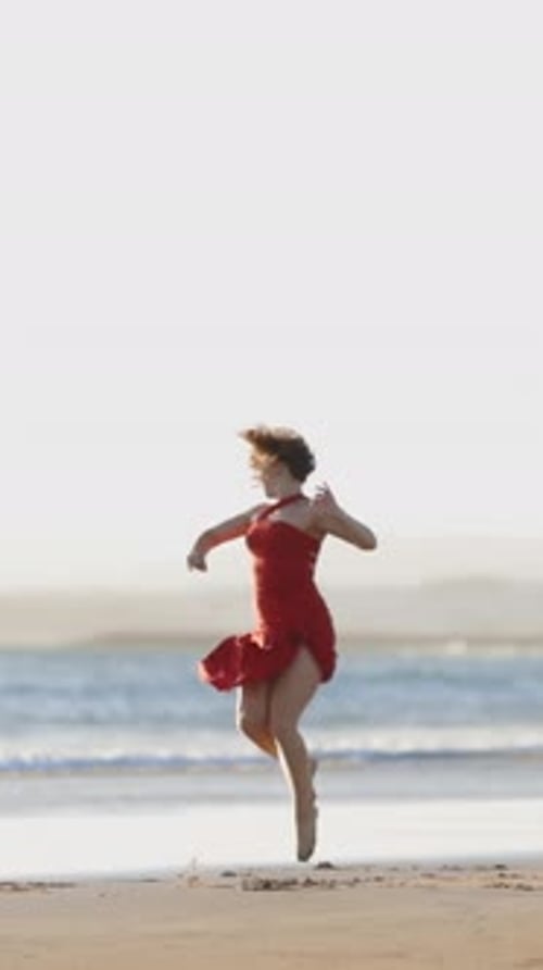 Woman Dancing on the Beach in Red Dress