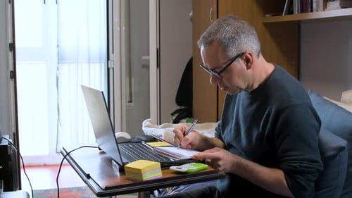 Adult Working on Laptop and Writing Notes