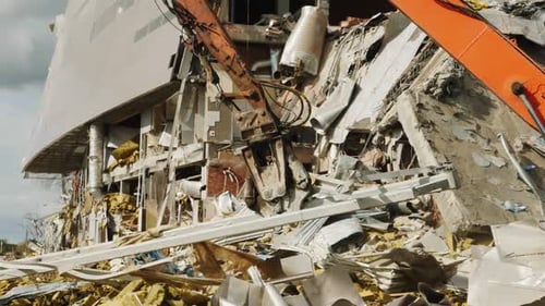 Une machine rouge moderne démonte les décombres d'une ancienne arène sportive