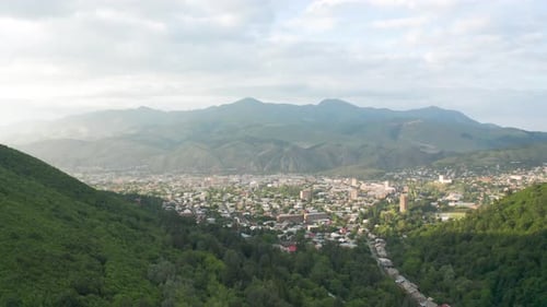 Aerial shot mountain town. Drone shot village town, township near green mountains.