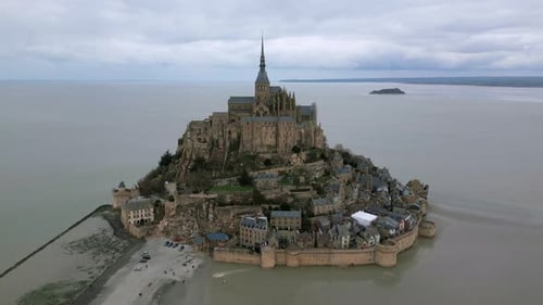 Drone orbiting around Mont Saint Michel on cloudy day, Normandy in France. Aerial high angle