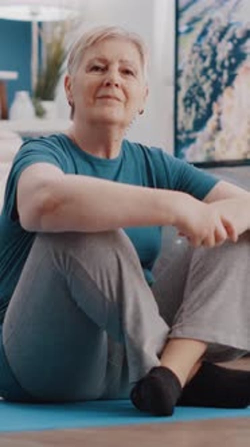 Senior Woman Sitting on Yoga Mat at Home