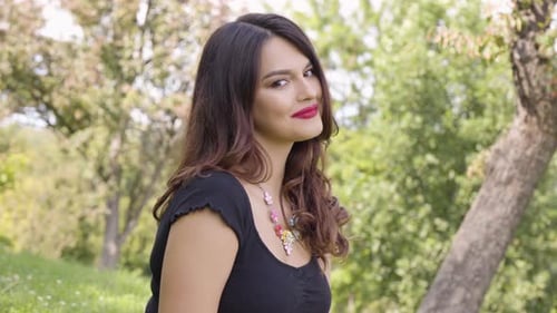 A Young Beautiful Caucasian Woman Smiles at the Camera in a Park on a Sunny Day