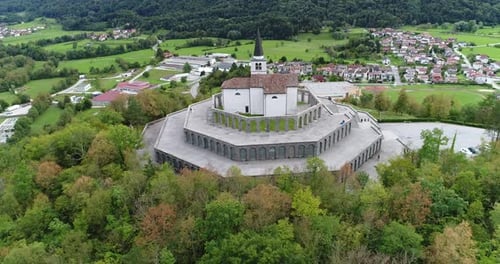 Aerial drone shot of a church on a hill with mountains in the background, 4k UHD