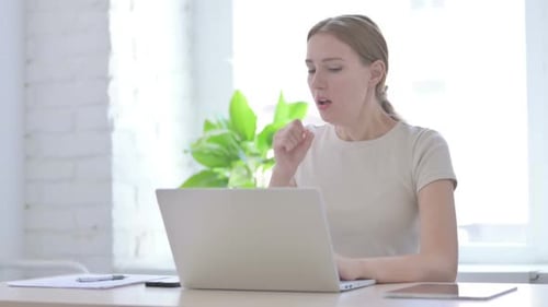 Young Woman Working on Laptop and Coughing