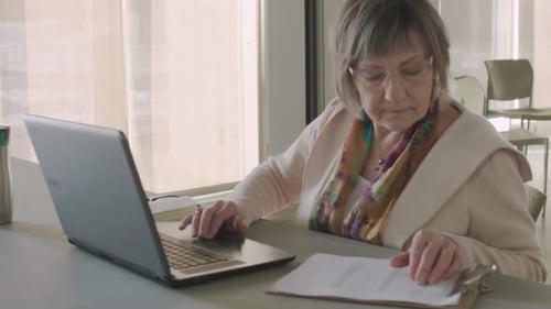 Senior Female Volunteer with Laptop and Board in Community Center