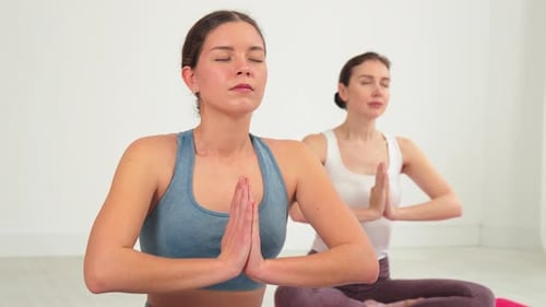 Women Meditating Indoors in a Bright White Studio