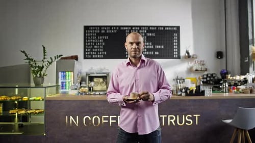 A Barista in a Cafe with a Cup of Coffee and a Smile Invites Visitors